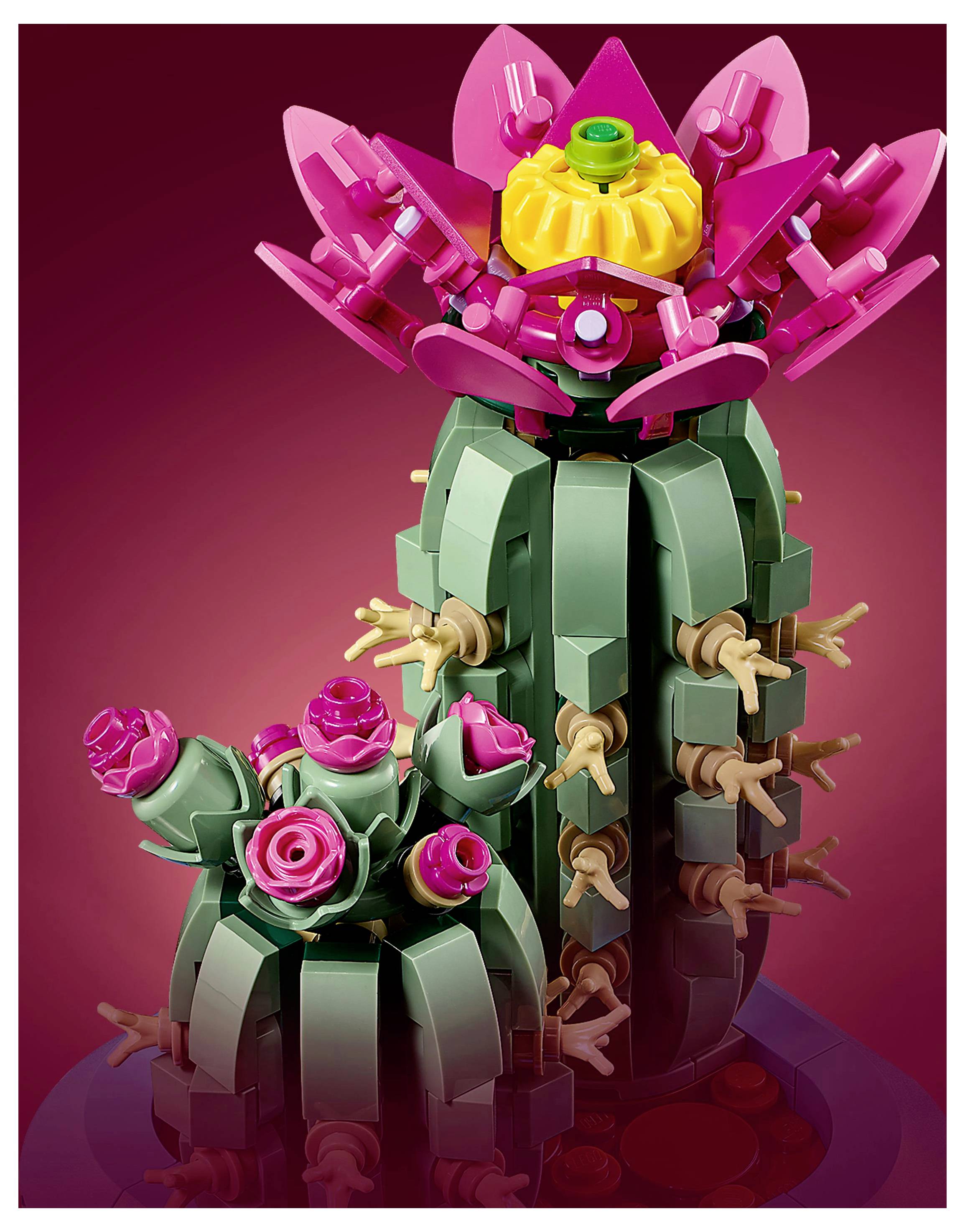 A colorful LEGO cactus with pink flowers and green segments against a gradient red background, resembling a blooming desert plant.