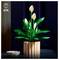 A decorative plant made of blocks on a table with a small striped bowl beside it, against a dark background.
