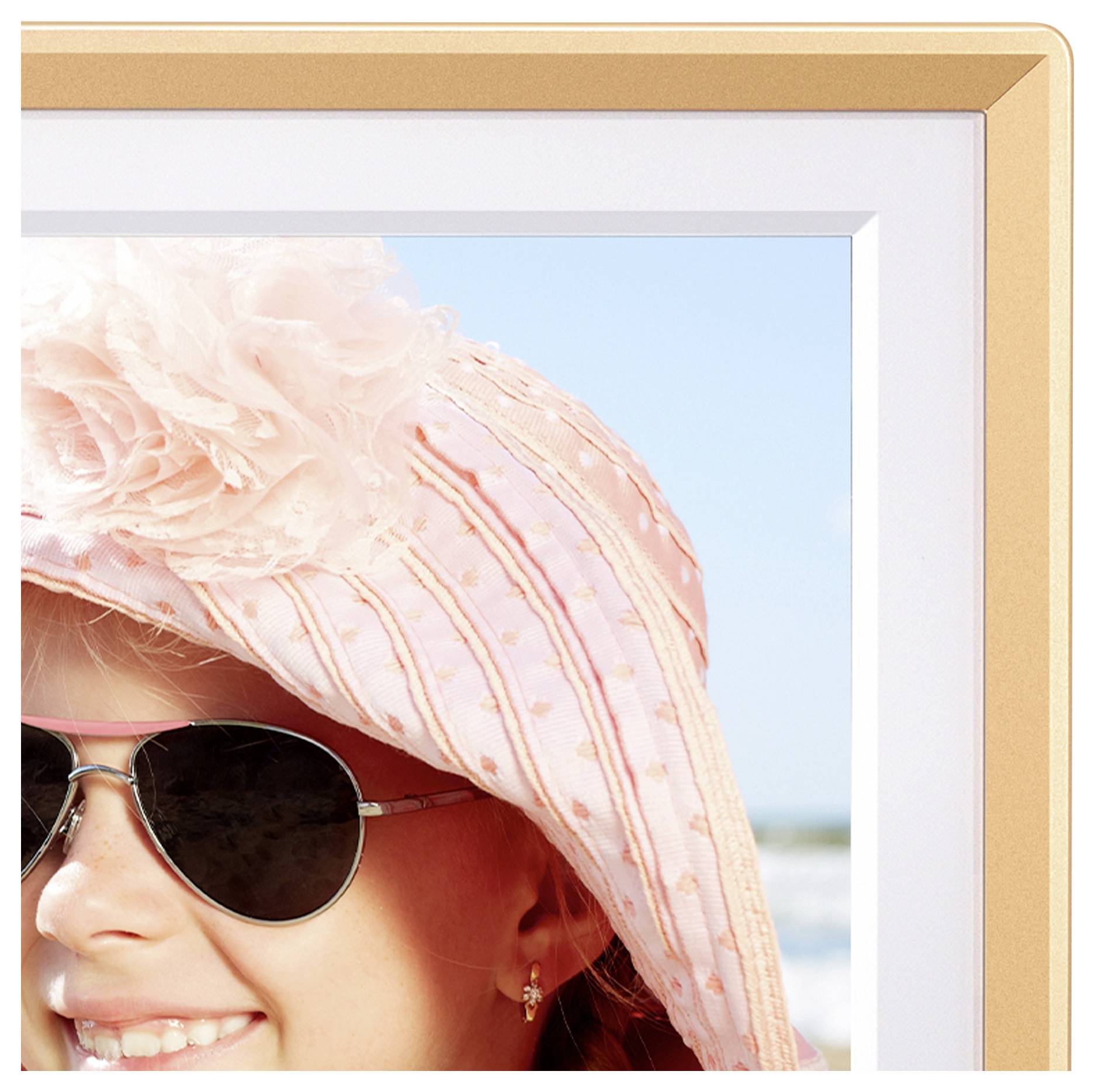 A smiling child wearing a hat and sunglasses enjoys a sunny day at the beach, partially visible against a backdrop of the ocean and sky.