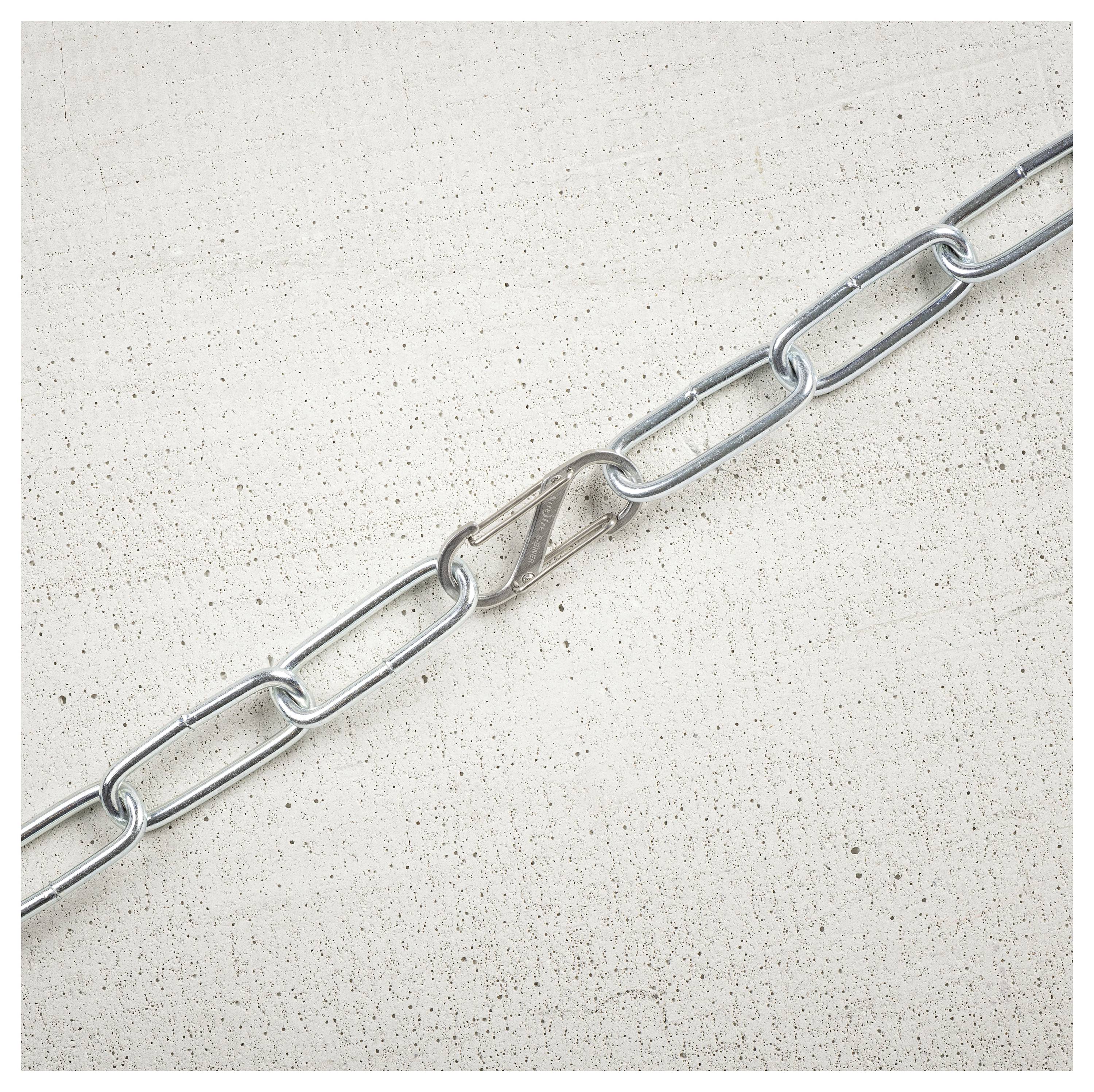 A metal chain with an open link lying on a textured concrete surface, illustrating vulnerability or breakage.