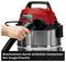 A vacuum cleaner with a red lid and black hose. A hand is manoeuvring the hose to activate the blowing function.