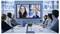 People in a conference room engaging in a video call displayed on a large screen, featuring two women and a man.