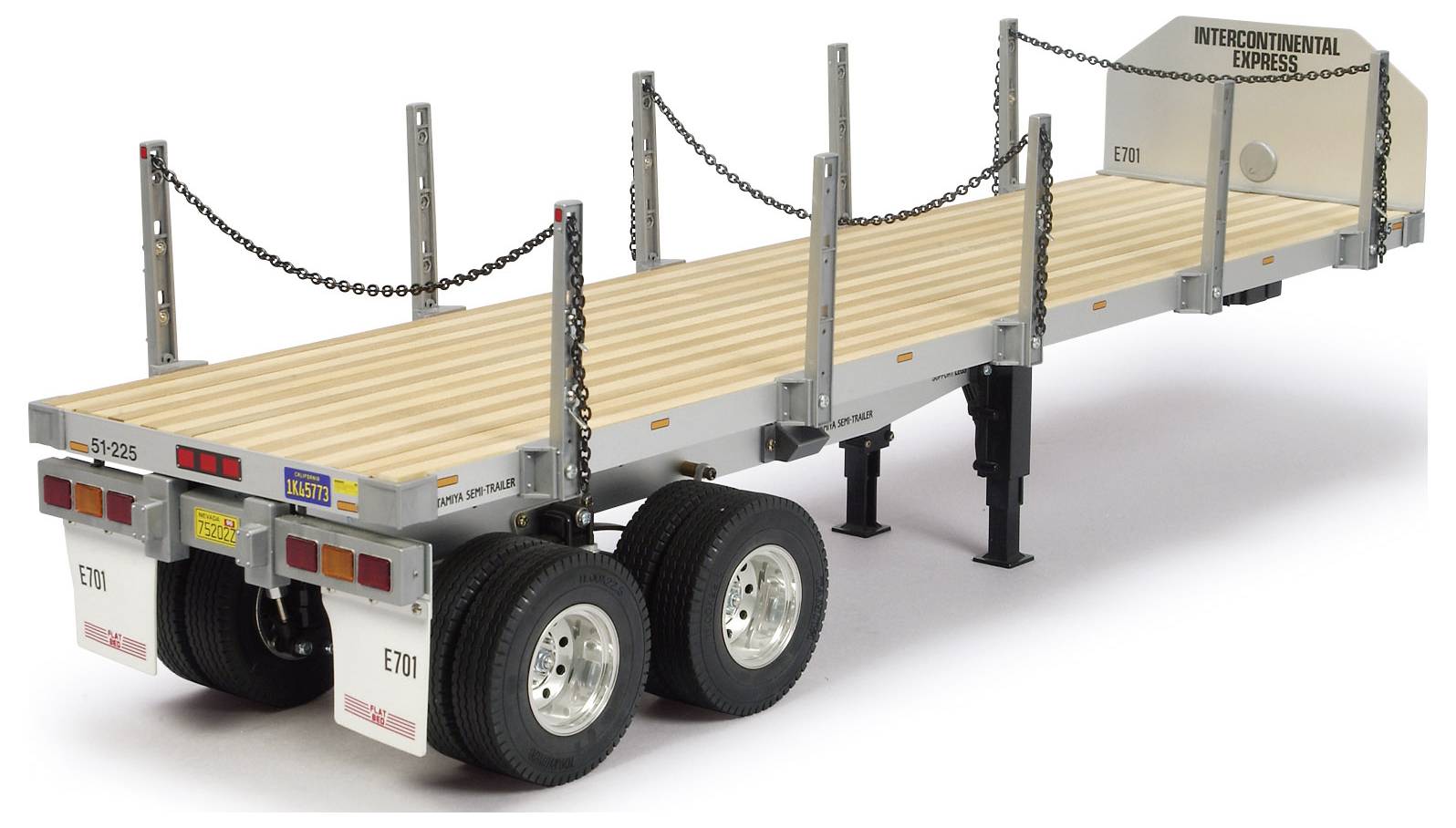 'A model of a flatbed trailer with chains and labels, designed for transporting heavy goods.'
