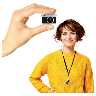 A woman in a yellow sweater smiles while holding a small camera, which is also shown enlarged by a hand in the upper left.