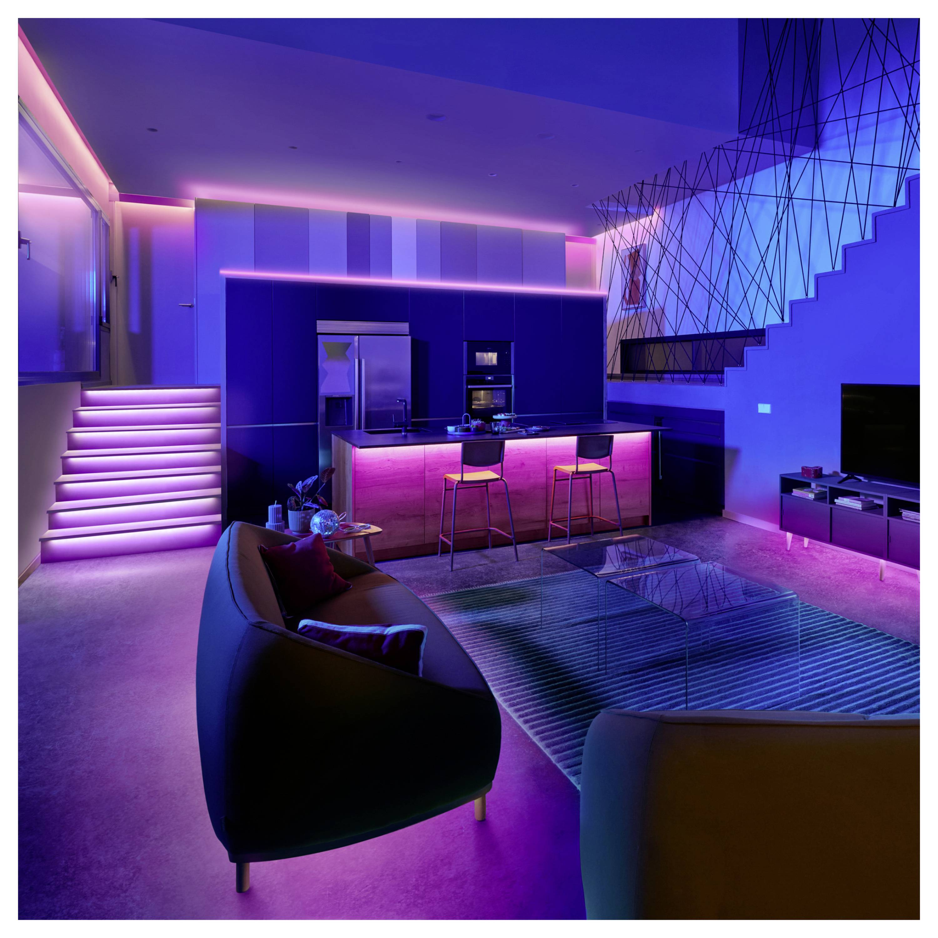 A modern living room and kitchen with neon lighting in pink and blue hues, featuring a staircase, two chairs, and a small glass table.