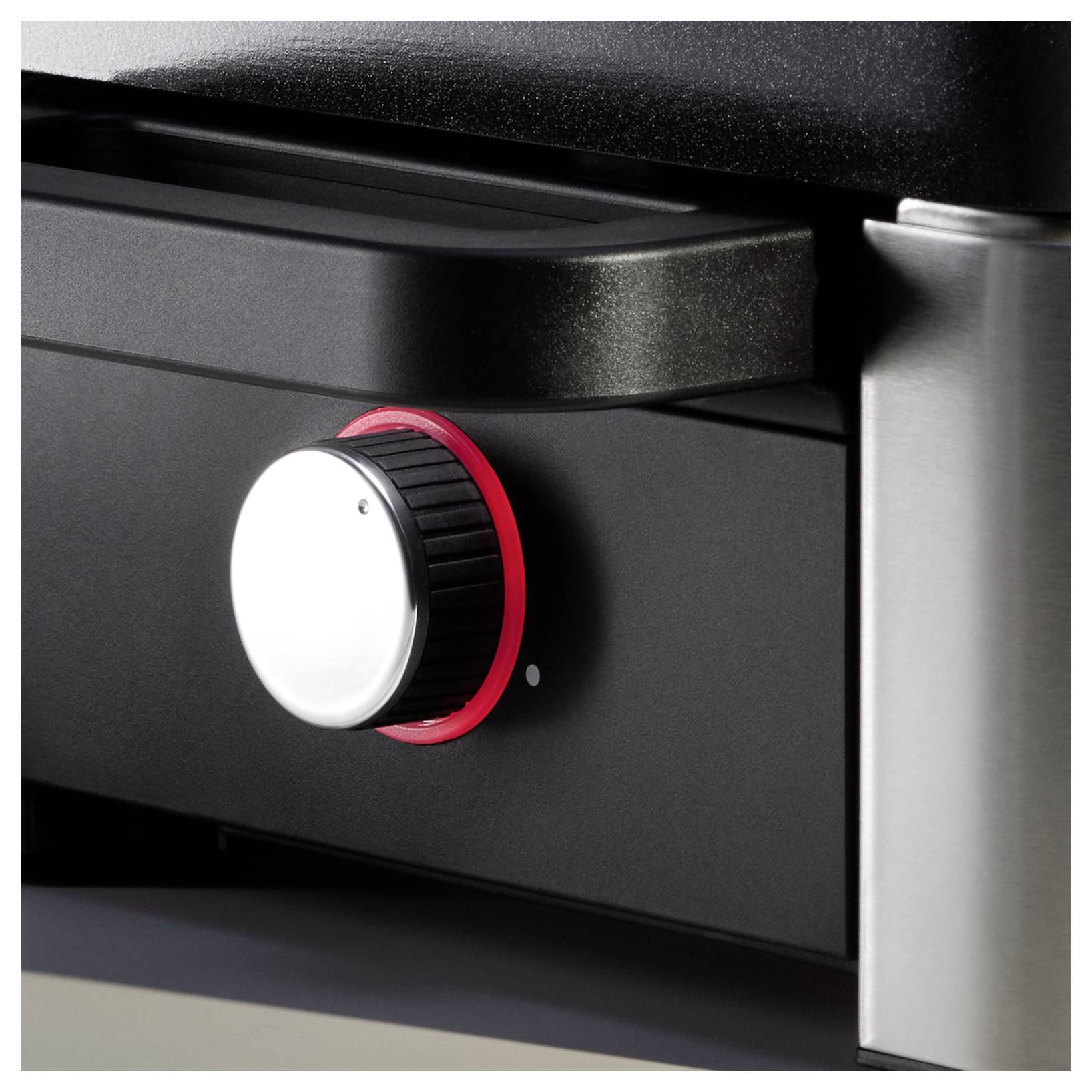A close-up of a black appliance with a silver knob surrounded by a red ring on the control panel, possibly for adjusting settings.