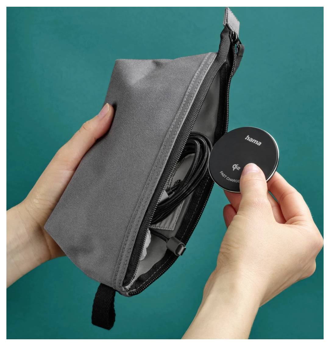 A person holds a small, gray pouch, pulling out a round, black wireless charger with 'hama' logo, set against a teal background.