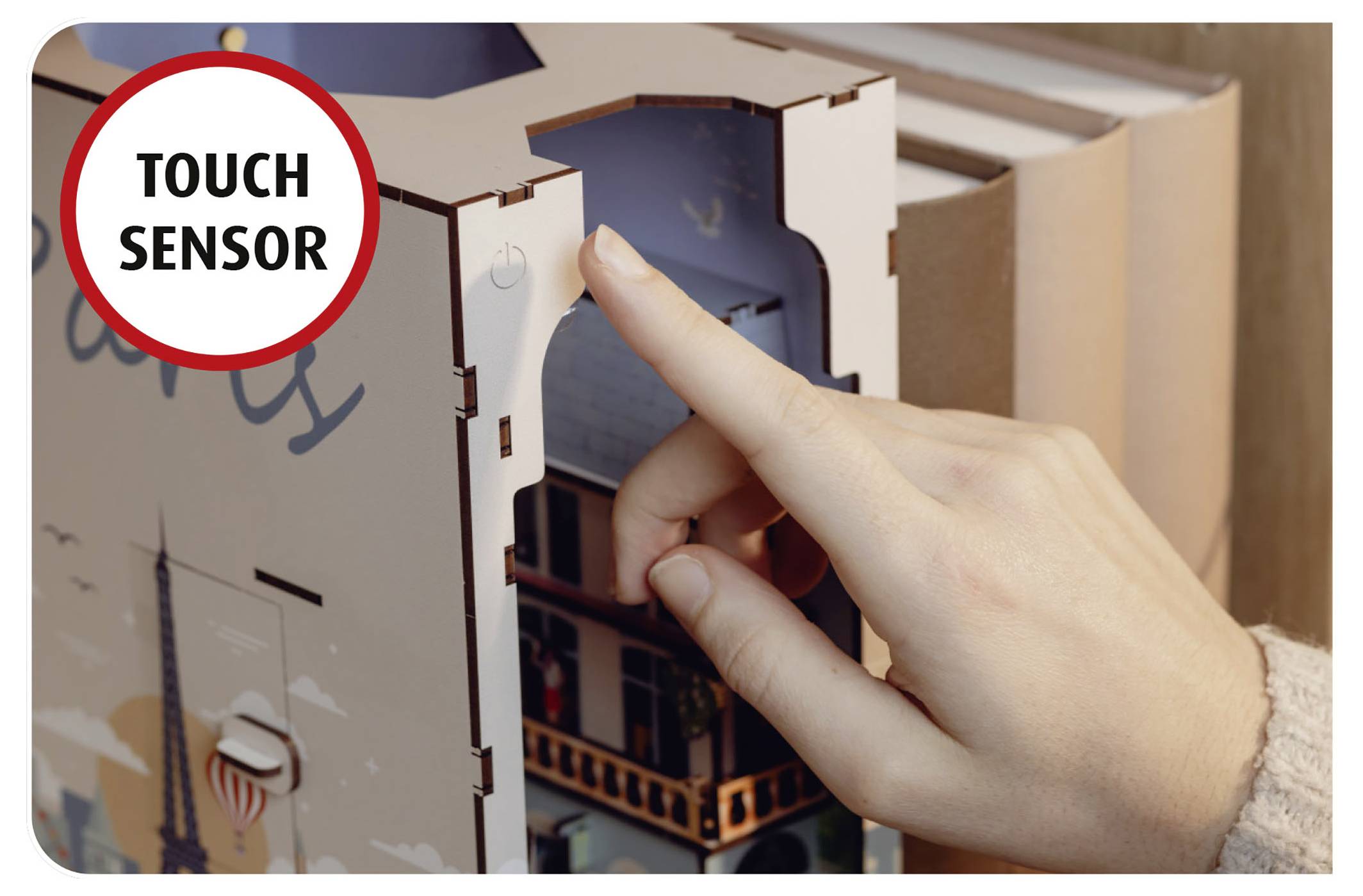 'A hand touching a circular sensor on a wooden model labeled "Touch Sensor," likely indicating interactive functionality.'