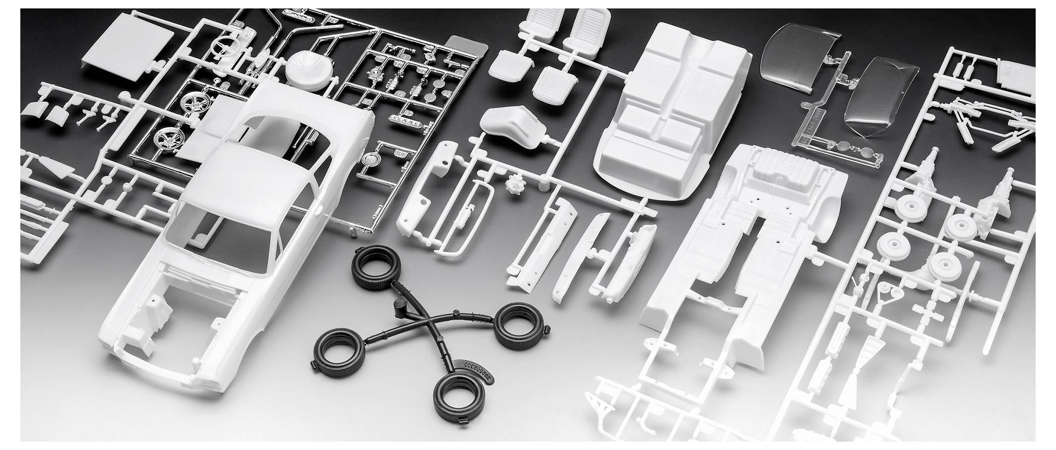 Model car kit with disassembled plastic parts including a car body, wheels, and interior components, laid out on a flat surface.