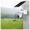 A solar-powered security camera mounted on a wall overlooks a rainy, grassy field with grazing deer in the background.