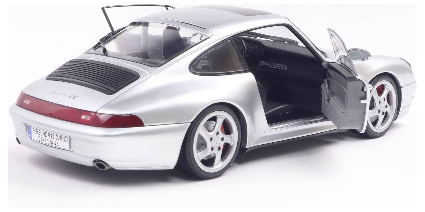 'Silver sports car with open driver's side door, showing sleek design and red brake calipers, parked on a white background.'