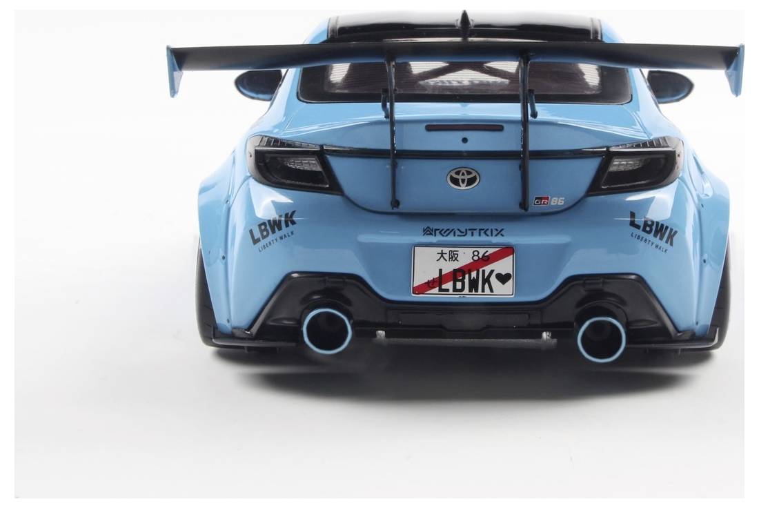 A modified blue sports car with a large rear spoiler and dual exhaust. Stickers on the back include 'LBWK' and a Japanese number plate.