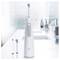 Electric toothbrush with two interchangeable heads on a bathroom counter, set against a blurred background of a modern sink and faucet.