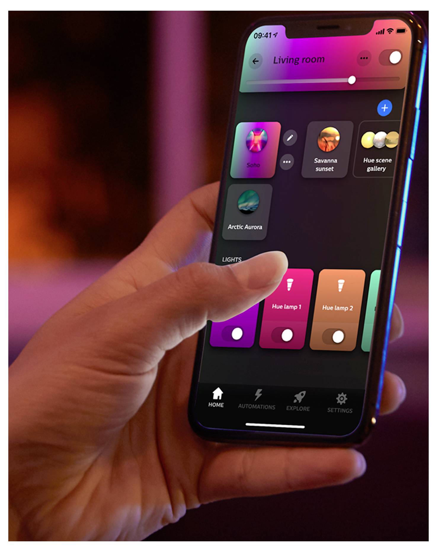 A hand holds a smartphone displaying a home lighting control app. The screen shows options to adjust room lighting scenes and brightness.
