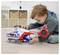 A young child playing with a brightly colored rescue-themed toy helicopter indoors, focusing intently on the toy's features.
