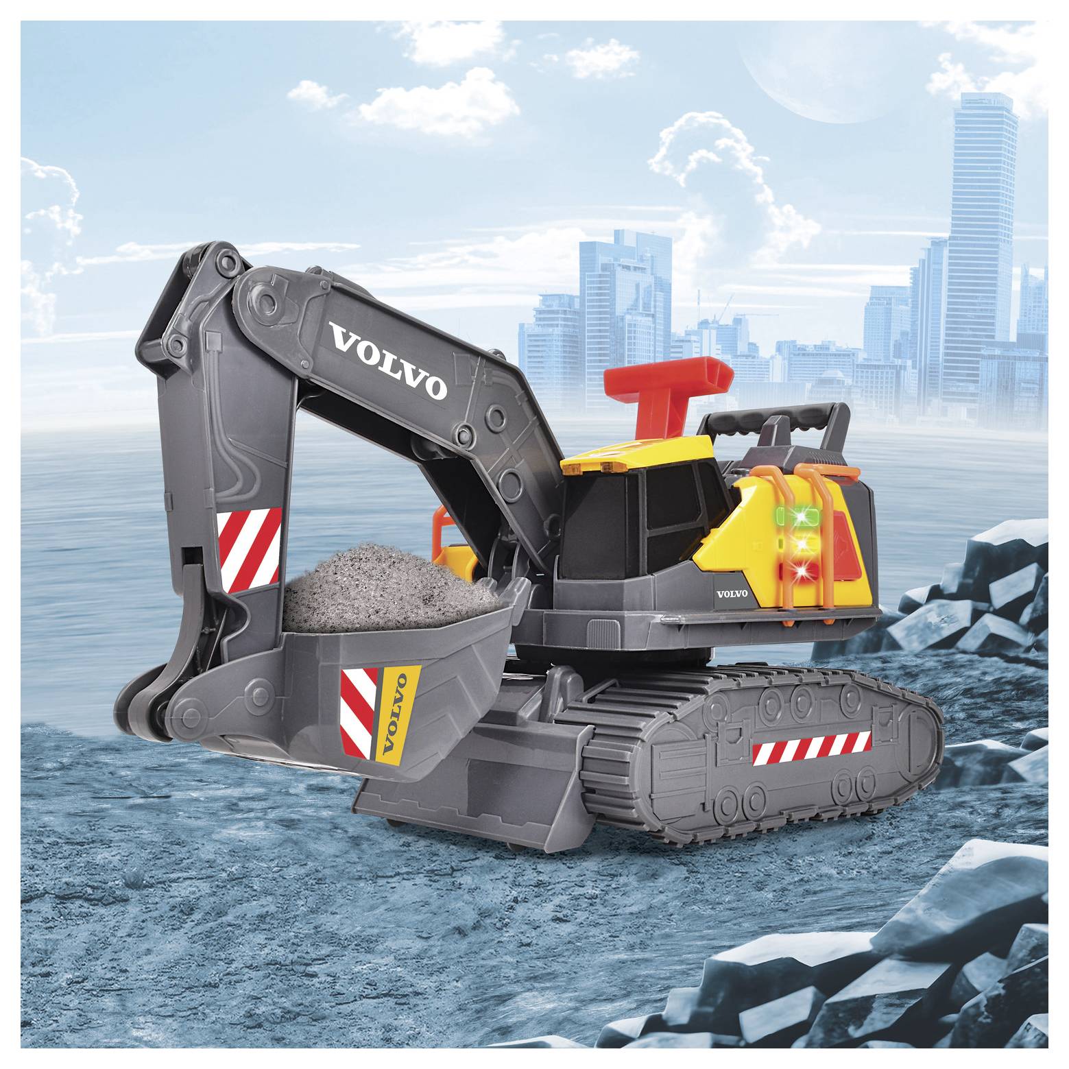 A toy excavator with the words 'Volvo' printed on it, shown with a scoop full of gravel. In the background, a city skyline is visible.