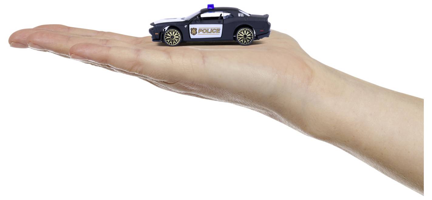 A person holds a small toy police car on their palm. The toy car is black with a police emblem and blue light on top.