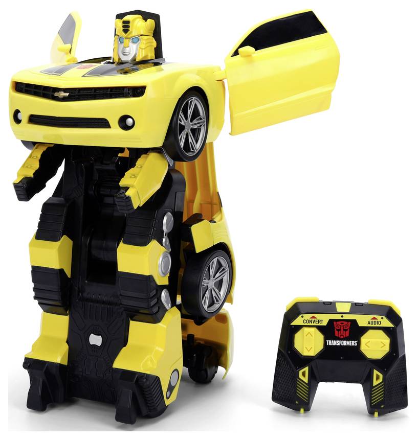 A yellow and black toy car transforms into a robot, standing upright. A remote control nearby shows buttons labeled 'Convert' and 'Audio'.