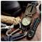 Outdoor gear including a hiking boot, compass, flashlight, multitool, carabiner, rope, and knife on a wooden surface, suggesting readiness for adventure.