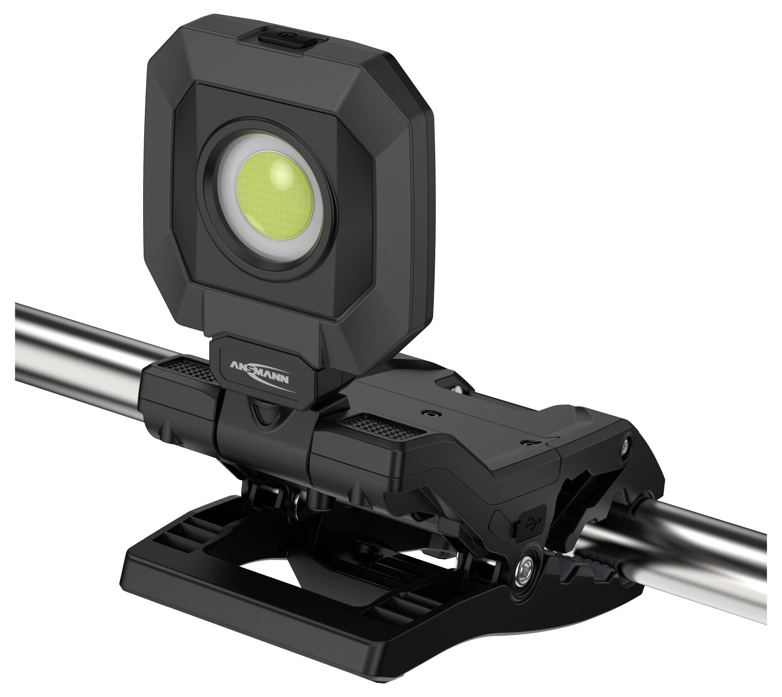 A compact, black work light with a clamp attachment is securely mounted on a metal pipe. The light features a central, round LED.