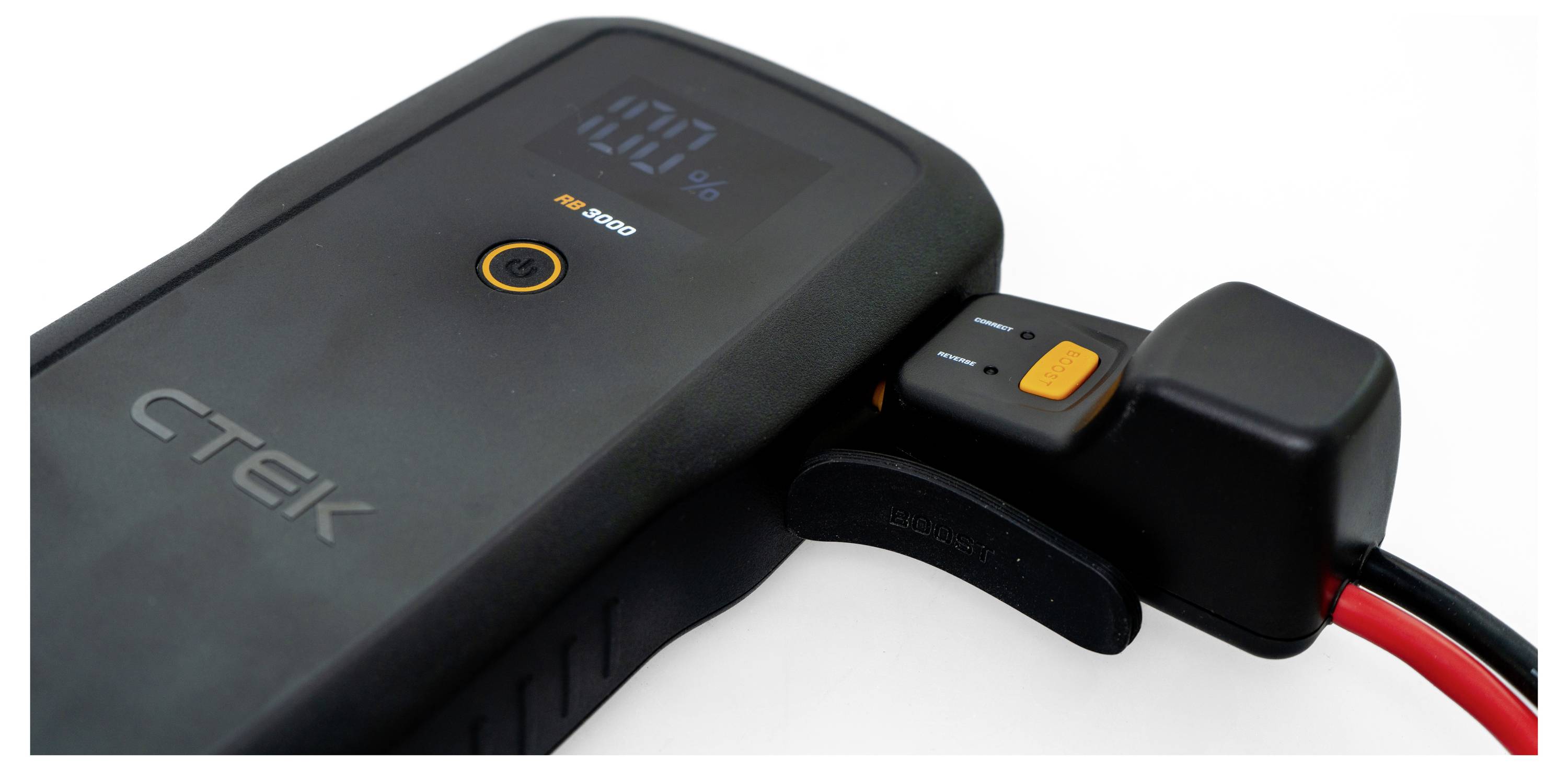 A black CTEK battery charger with an LED display shows a '100%' charge. A connected cable is visible with an orange button.