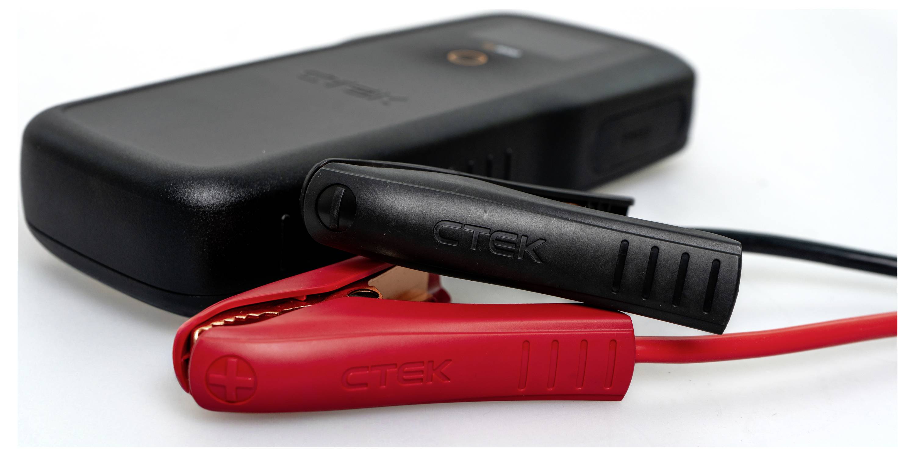 A portable battery charger with red and black clamps attached, used for charging or jump-starting a vehicle battery.