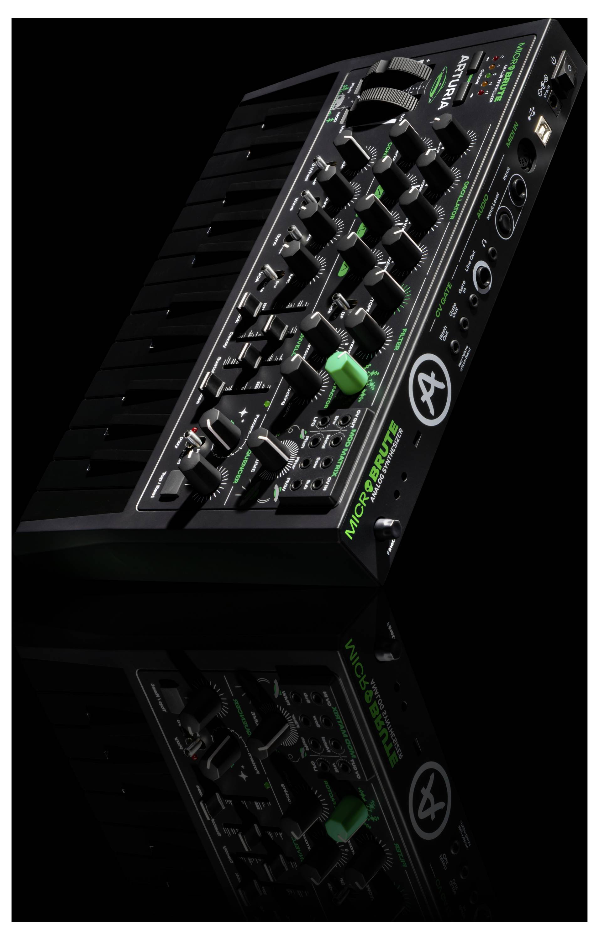 A black synthesizer with multiple knobs and dials, featuring green accent lights, set against a black background with a reflection below.