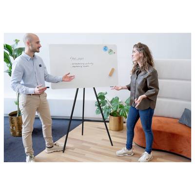 Two people engage in discussion at a whiteboard listing 'Next steps: brainstorming activity, marketing review' in an office setting.