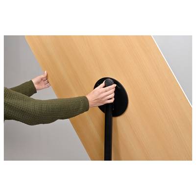 A person in a green sweater uses a hand crank on a large wooden panel, possibly adjusting its position or angle.