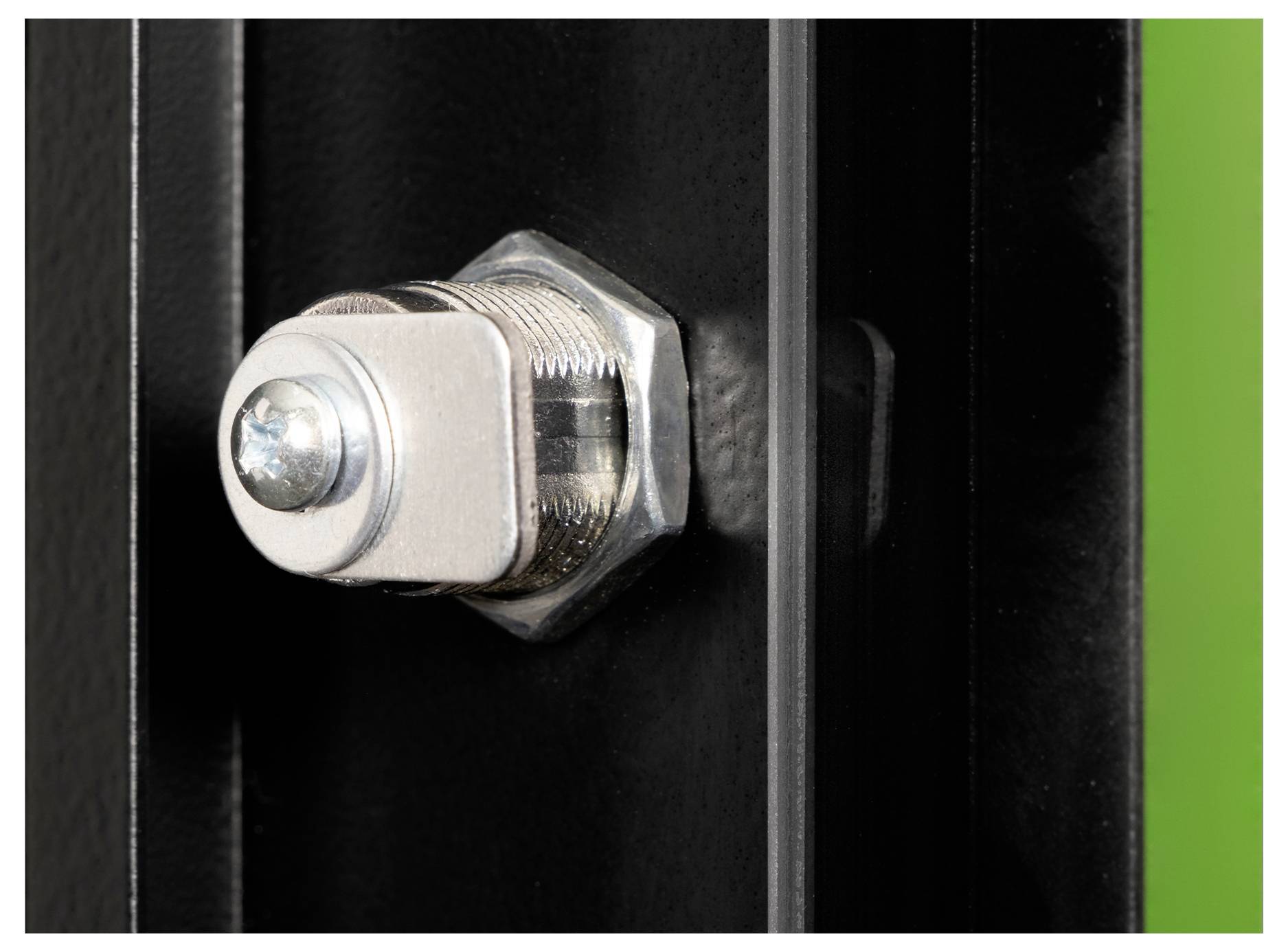 'Close-up of a metallic bolt secured through a black panel with a green background on the right side, illustrating hardware detail.'