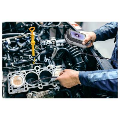 Mechanic uses a handheld inspection camera to examine a car engine with the cylinder head removed, checking internal components.<br>