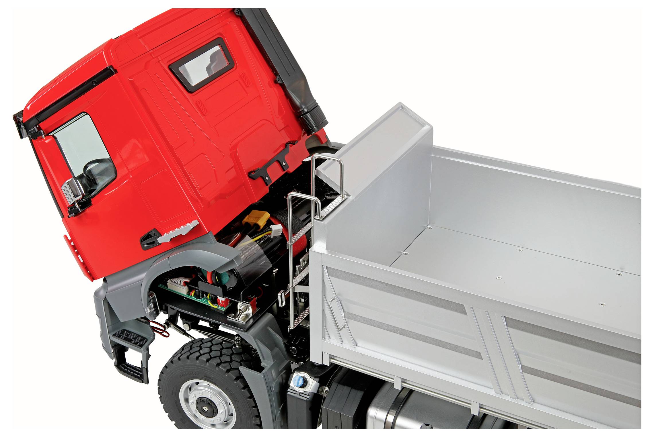 A bright red truck with an open hood reveals inner mechanical components, next to an empty silver cargo bed, viewed at an angle.