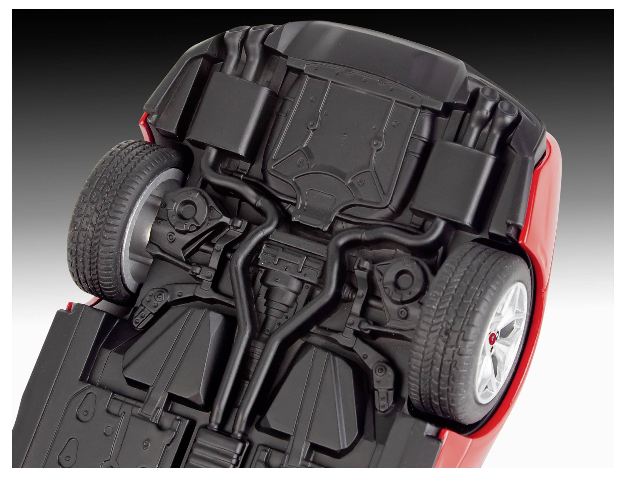 The image shows the underside of a red toy car, detailing the wheels and suspension systems on a gradient gray background.