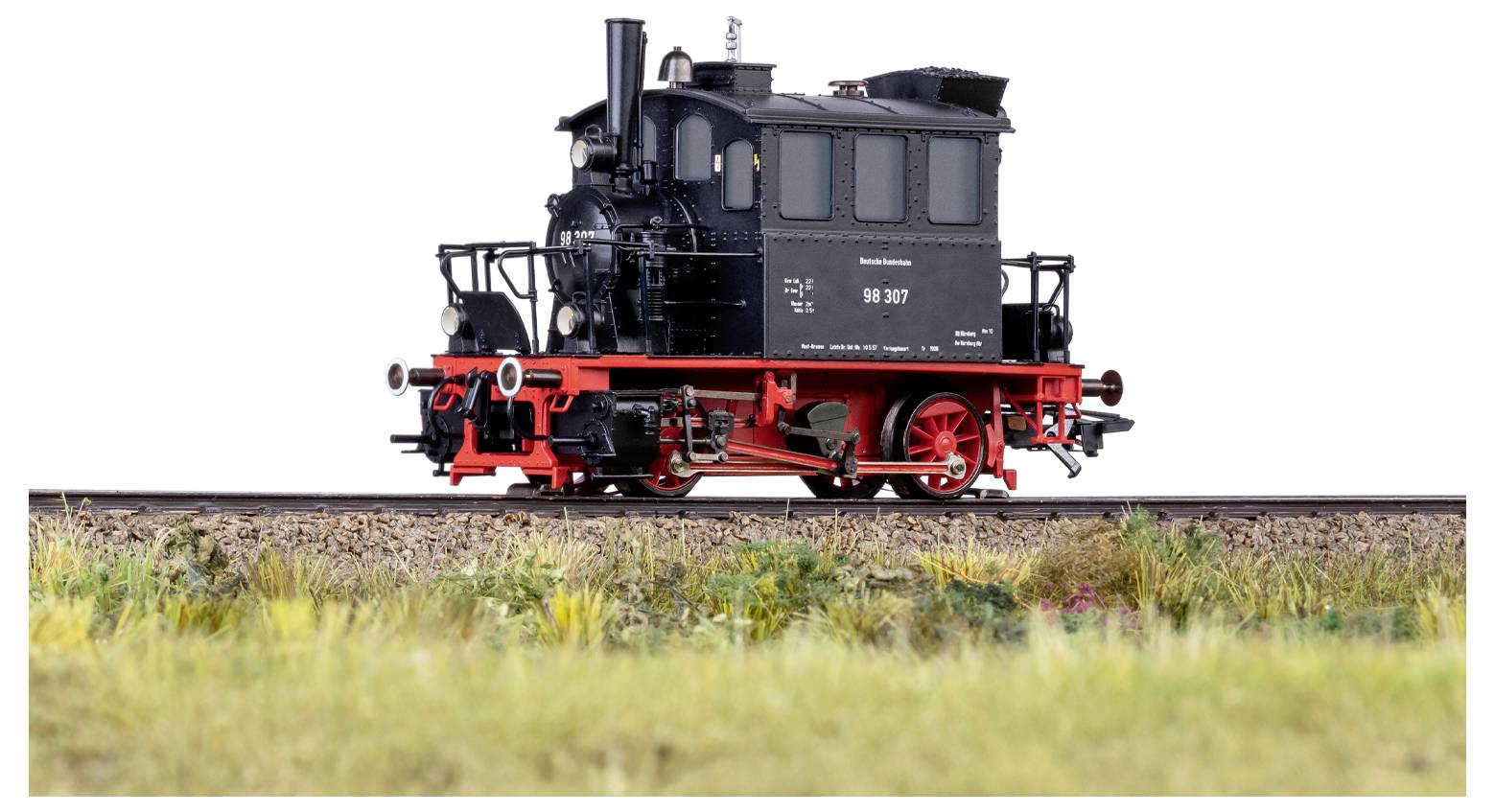 A detailed model of a vintage black steam locomotive with red wheels, sits on a section of railway track.