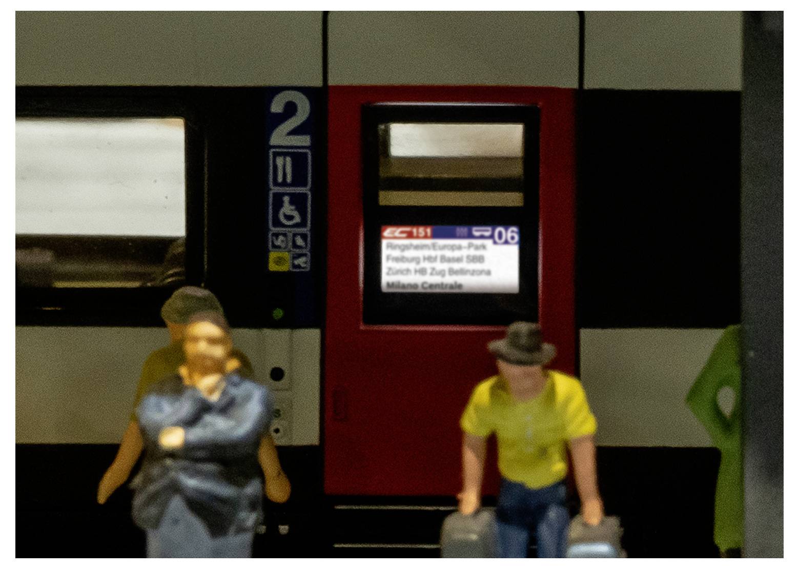 'Train with passengers boarding. Display shows IC151 to Milan Centrale, stopping at Freiburg, Basel, and Zurich. Car number 2.'