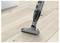 A cordless vacuum cleaner on a wooden floor near a kitchen cabinet, showcasing its mobility and suitability for cleaning hard surfaces.