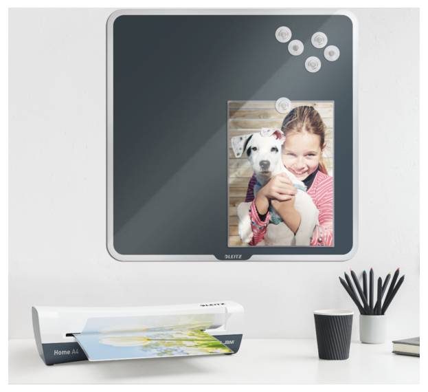 A young girl smiles while holding a puppy, displayed on a glossy photo print. A blank square bulletin board with magnets is mounted above.