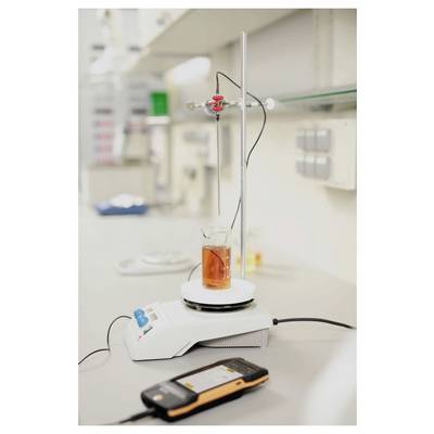 A lab setup with a beaker of orange liquid on a magnetic stirrer, connected to a probe. A digital device is in the foreground.