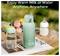 'A green portable bottle warmer on a table with a digital display reading 104°F, surrounded by a water bottle and a baby bottle.'