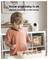 A young child plays with toys in a room. Text above reads: 'Know your baby is ok anytime anywhere in the house.' A camera is mounted on the wall.