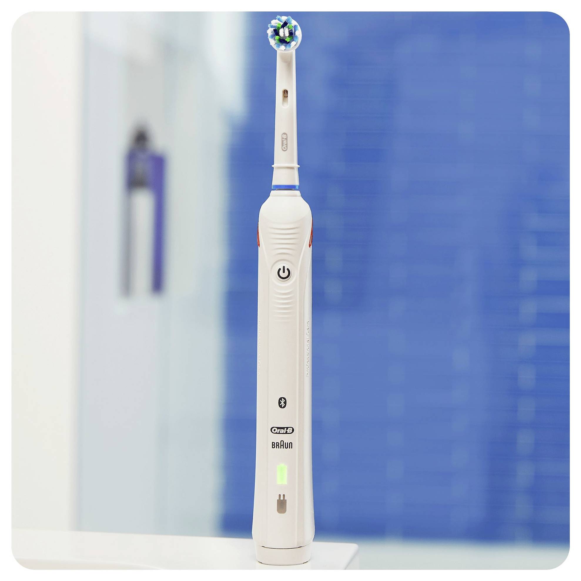 A white electric toothbrush with a round head stands upright against a blurred blue background.