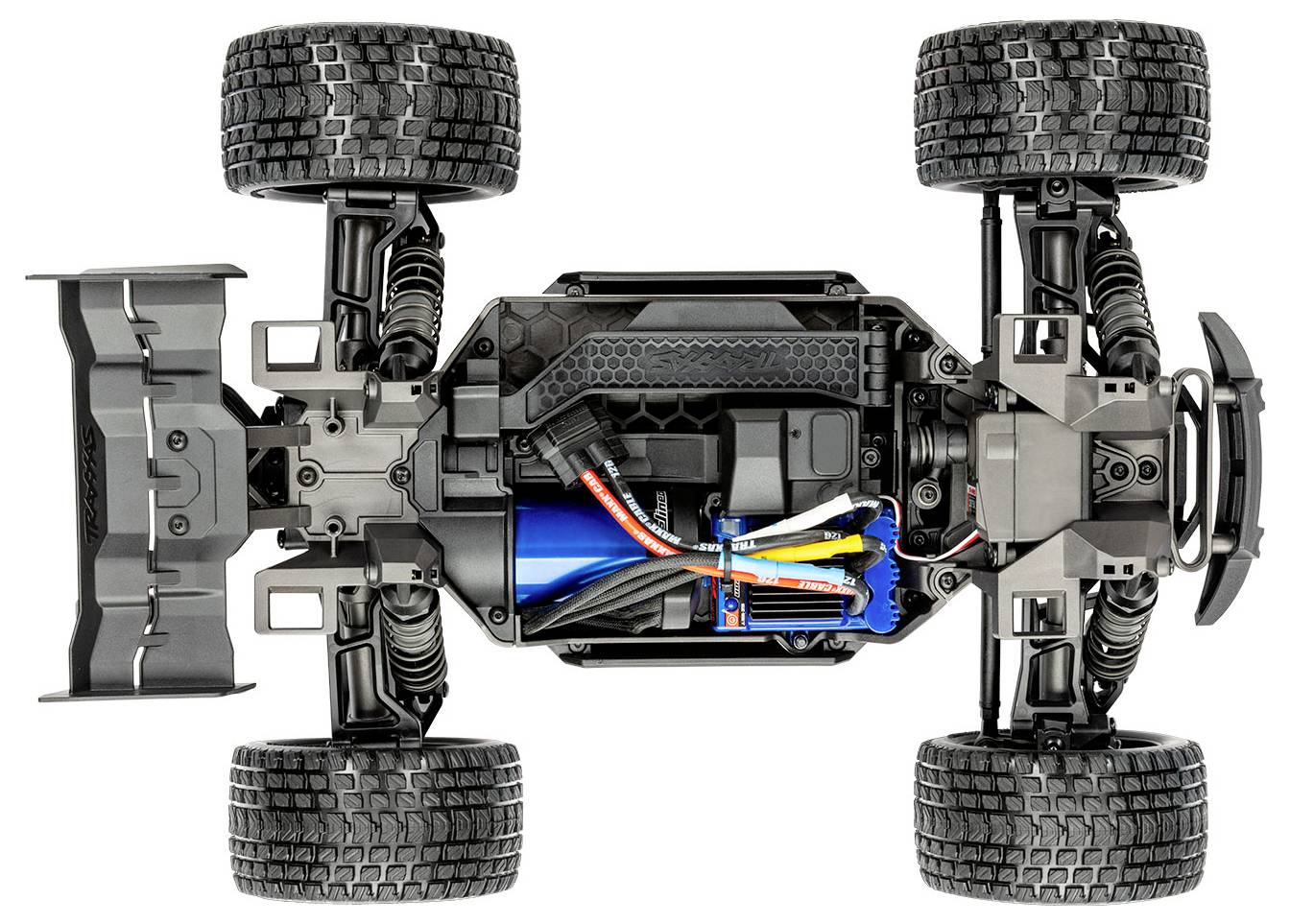 Overhead view of a remote-controlled car chassis showing detailed components: large tires, battery, wiring, and suspension system.