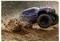 A blue and red remote-controlled car speeds through sandy terrain, kicking up dirt, showcasing its off-road capabilities.