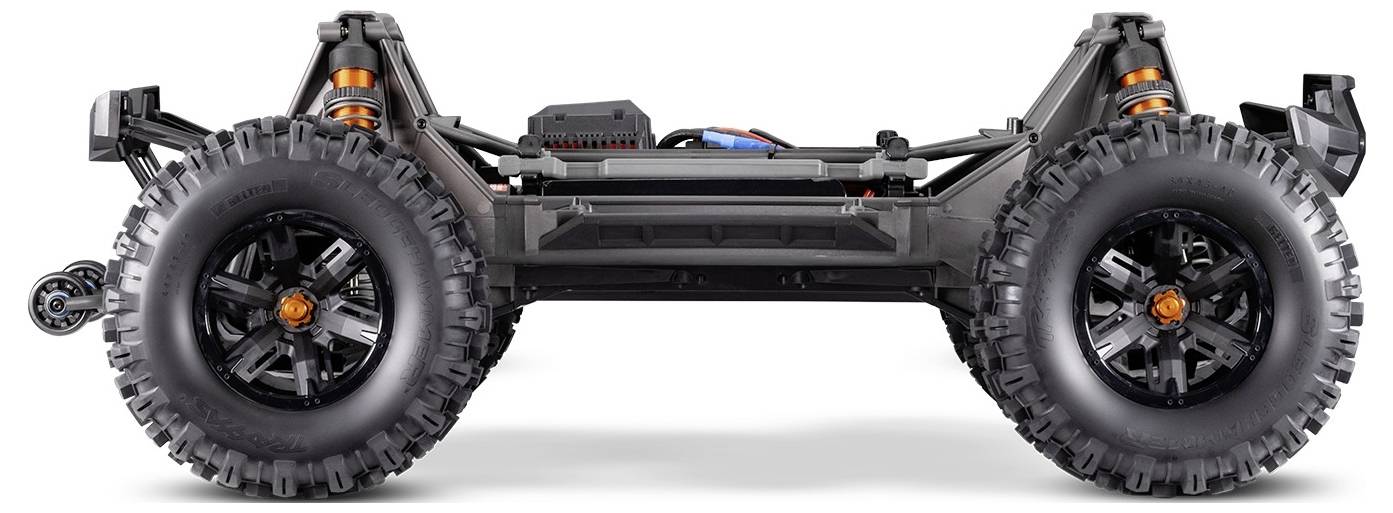 Side view of a rugged off-road remote-controlled vehicle chassis, featuring large knobby tires, visible suspension and internal wiring.