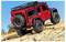 A red toy off-road vehicle on rugged terrain, showcasing its large tires and detailed design under a clear blue sky.