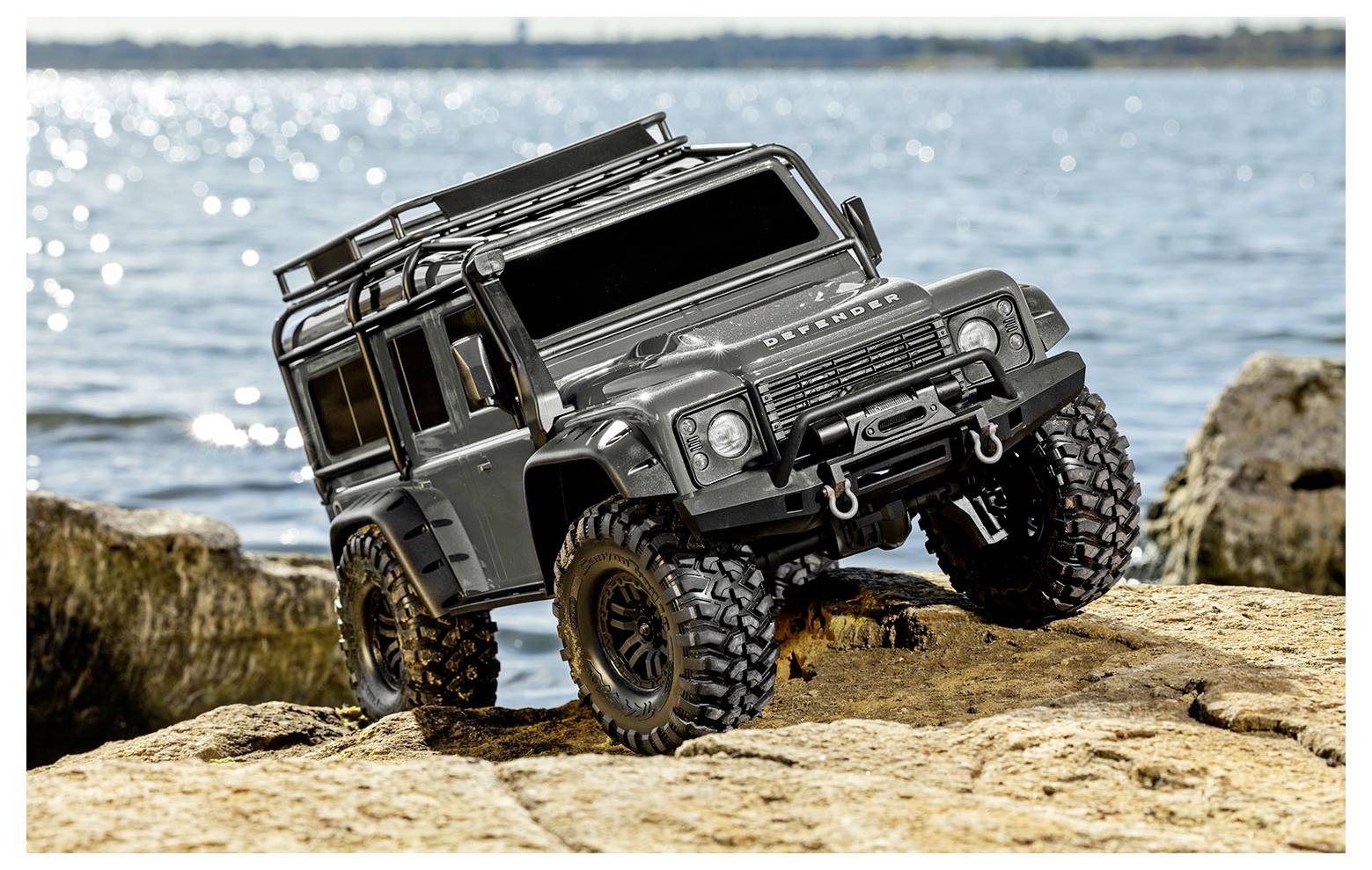 A toy off-road vehicle on rocky terrain by the water, depicting adventure and exploration.