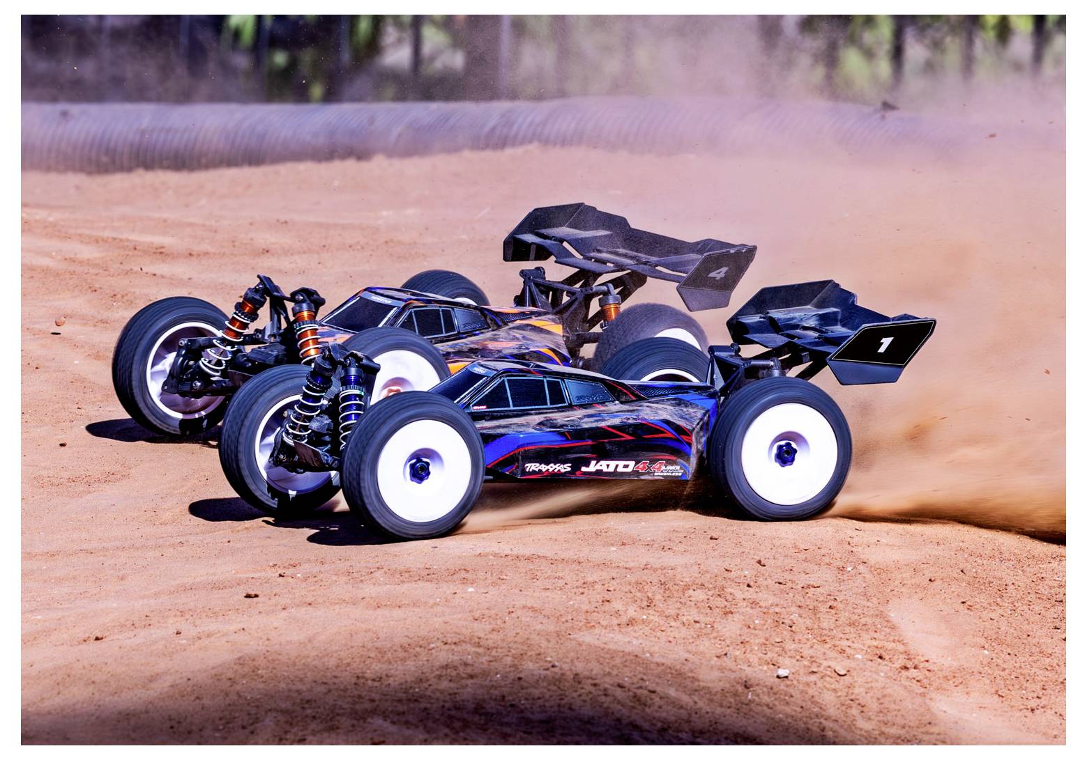 Two remote-controlled cars race on a dusty track, kicking up dirt. One car leads slightly, showcasing speed and competitive action.