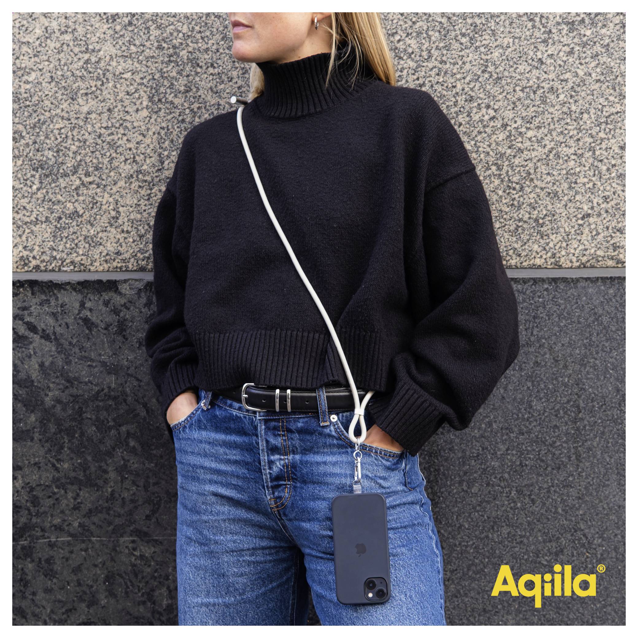 A person in a black sweater and jeans, using a white cord as a phone holder. The phone hangs by their side. 'Aqiila' logo in corner.