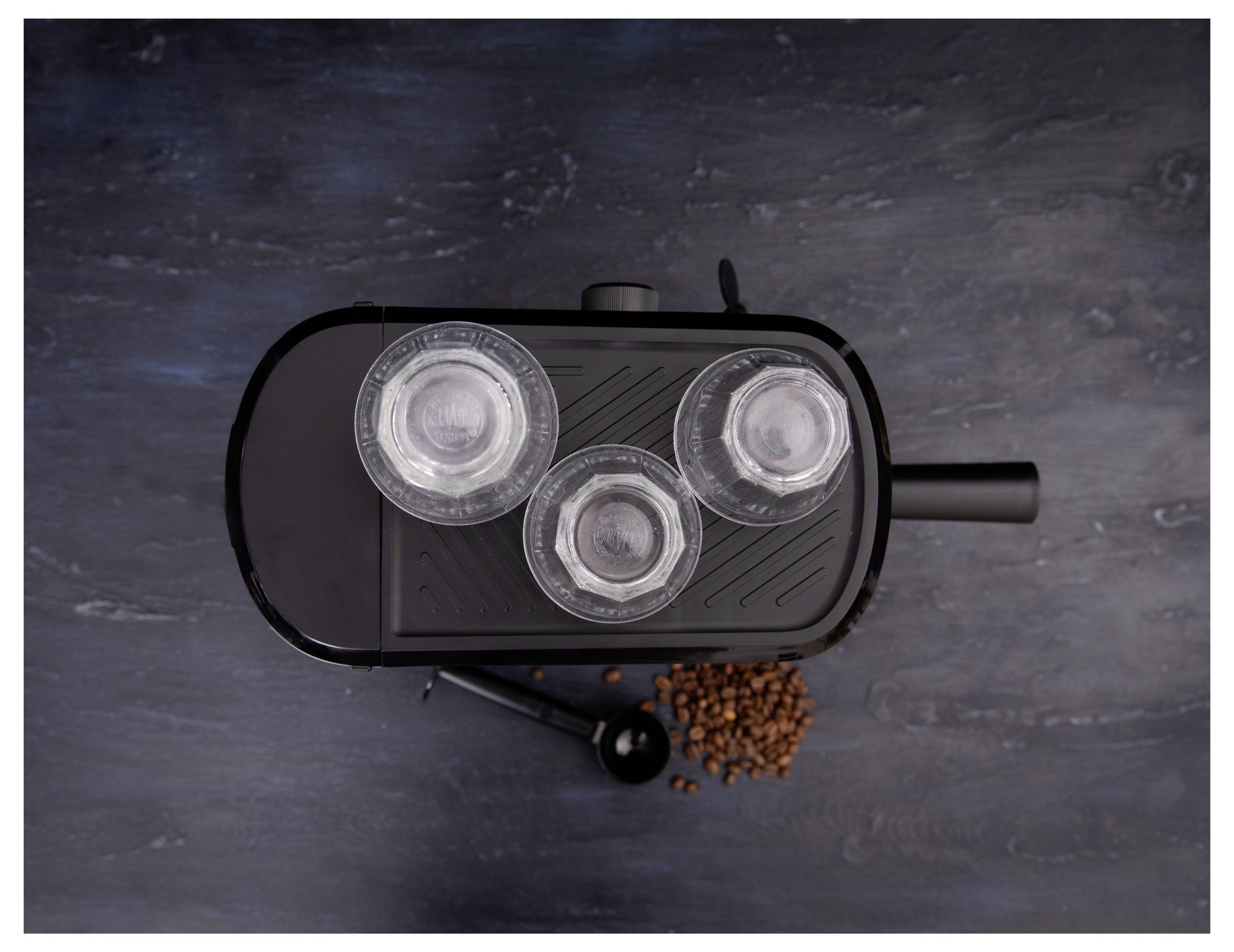 Top view of a coffee maker with three glass bowls on a slate surface, surrounded by scattered coffee beans.