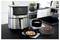A modern kitchen with a stainless steel air fryer displaying '180°' and '15:00'. Nearby, a pizza, a casserole, and skewers are prepared.